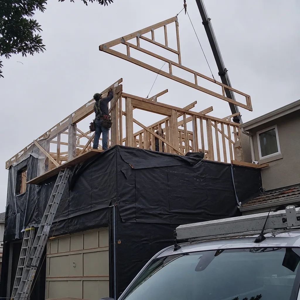Contractor guiding a roof truss installation during a residential home addition project